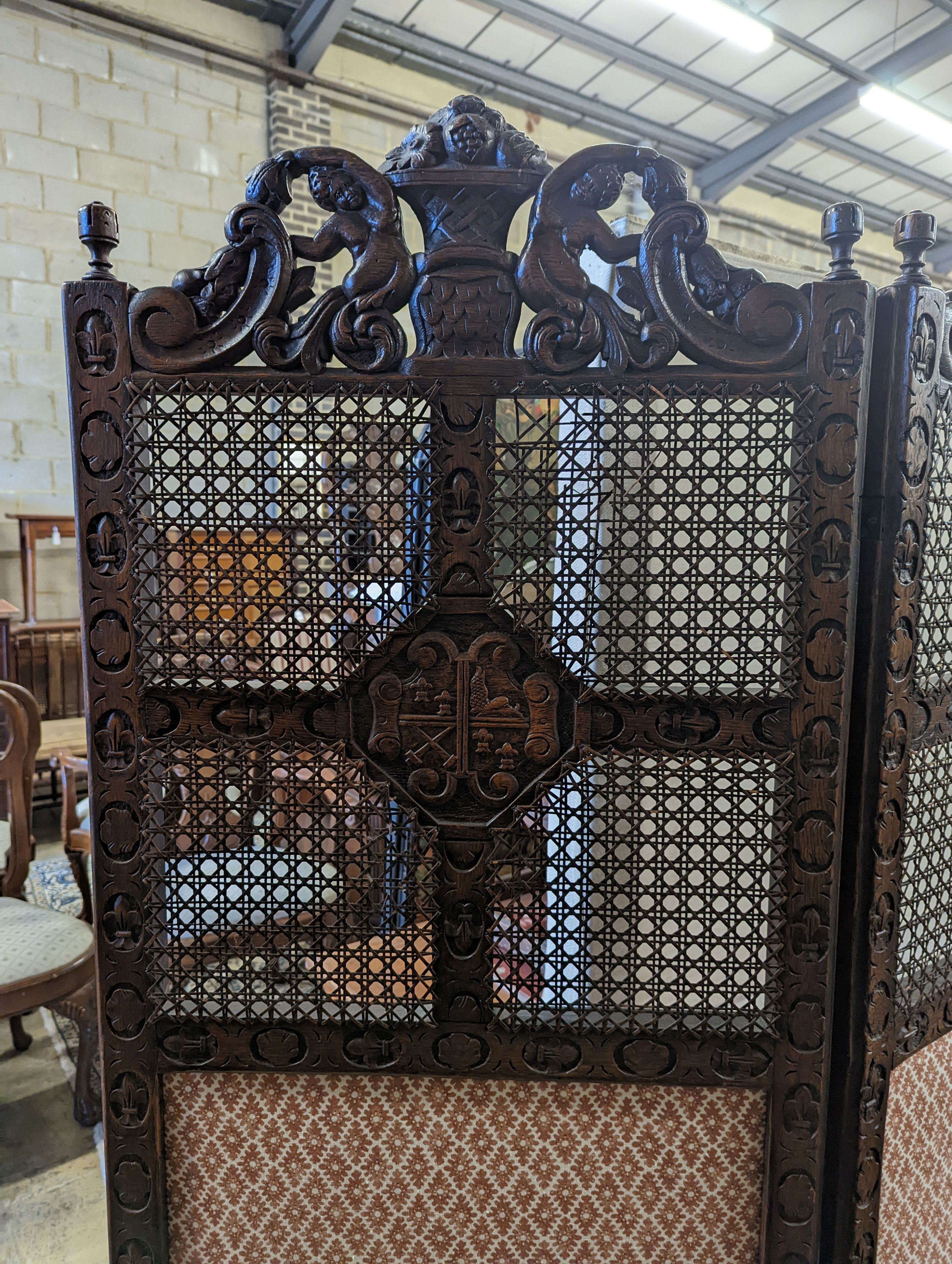 A 1920's Carolean style oak and cane work two fold dressing screen, each panel width 60cm, height 182cm